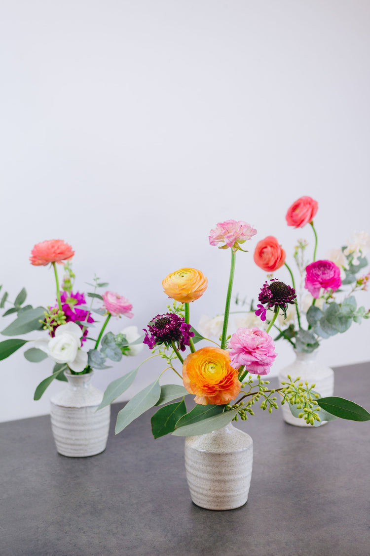 Three bud vases with bright flowers.