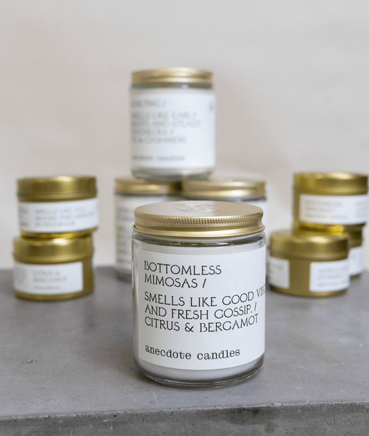 Anecdote brand candles with white labels and gold lids.