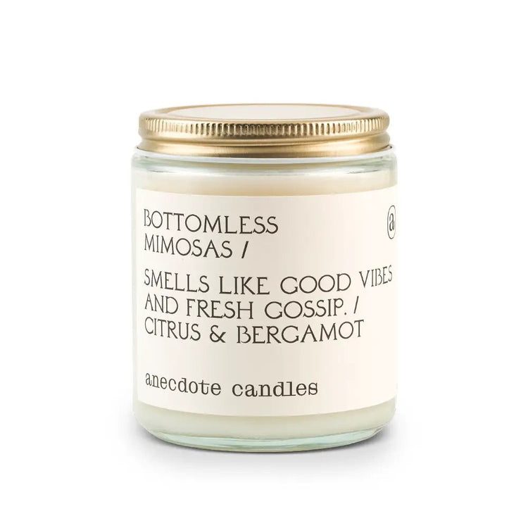 White Anecdote candle with label reading Bottomless mimosas / Smells like good vibes and fresh gossip. / Citrus & bergamot.