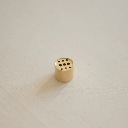Small brass incense holder with three rows of holes: first row is three small holes, middle row is three larger holes, and bottom row is three small holes again.