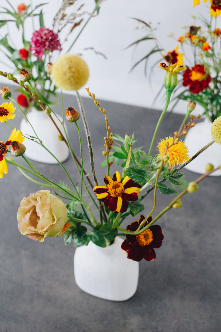 Small floral arrangements in white bud vases.